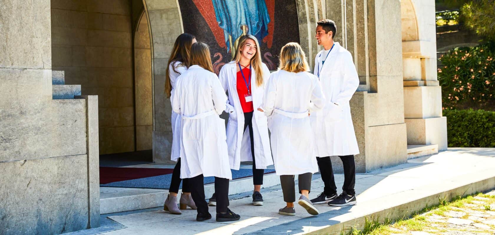 Students standing outside the entrance to a hospital chatting.
